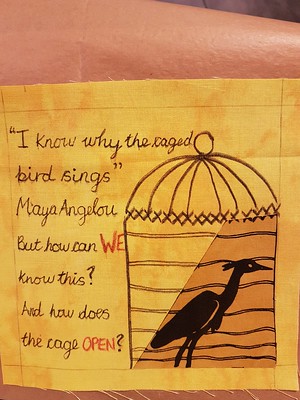 Completed bird sample quilt block with appliqued bird, drawn cage and text